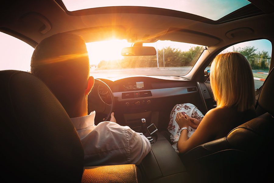 Its-Your-Turn-to-Earn-Rewards-Husband-and-Wife-Sitting-in-the-Front-Seat-of-a-Car-Driving-into-the-Sun