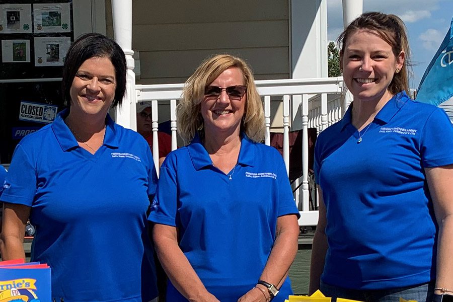 About Our Agency - Trisha, Denise and Barbara Standing Together at a Volunteer Event on a Sunny Day