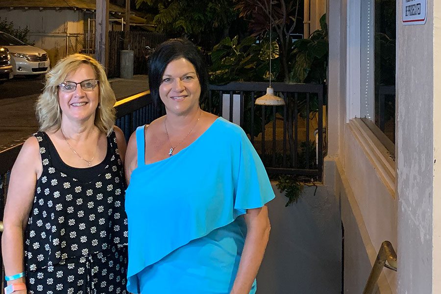 About Our Agency - Denise and Trisha Standing Together Outside a Restaurant in the Evening