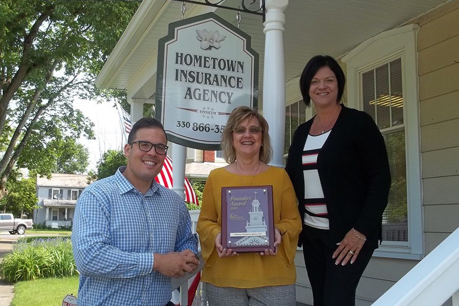 About Our Agency - Denise and Trisha Standing on Stairs Together in Front of Their Office Holding an Award With a Colleague